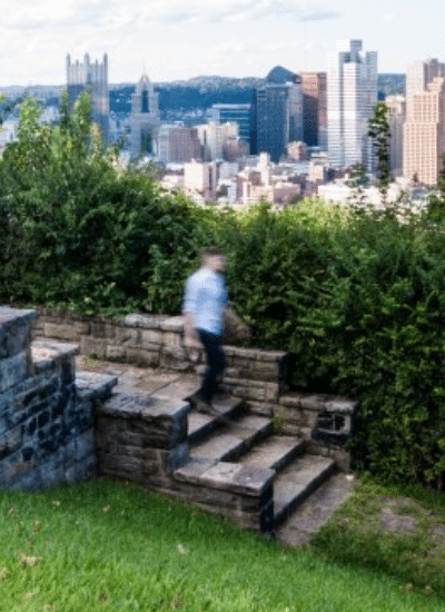 Person walking down steps at Emerald View Park with view of Pittsburgh skyline