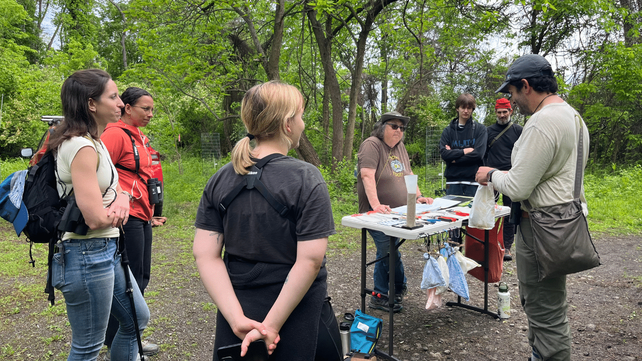 Bird Lab Hays Woods A group of people learn about bird banding while gathered around a table in Hays Woods Park.