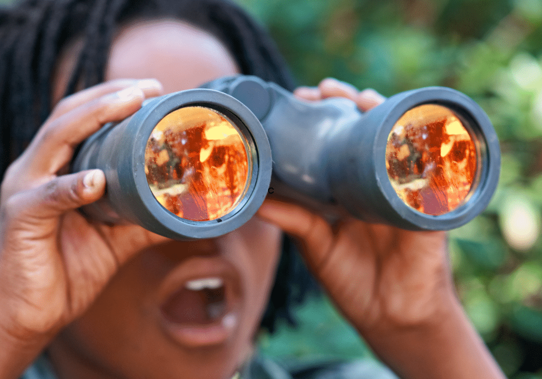 A child looking through binoculars in a natural setting.